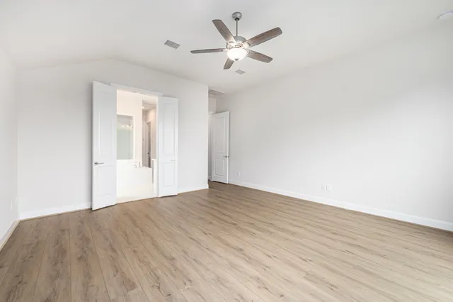 an empty room with wooden floor and ceiling fan