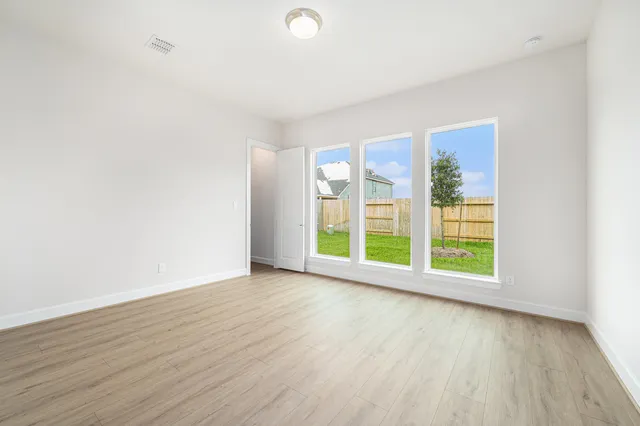 an empty room with wooden floor and windows