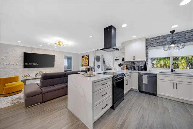 a kitchen with stainless steel appliances granite countertop a sink dishwasher stove and white cabinets with wooden floor