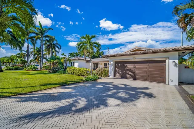 a front view of a house with a yard and potted plants