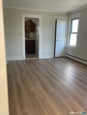 an empty room with wooden floor cabinet and windows