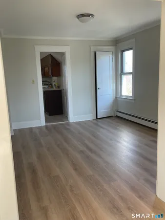 an empty room with wooden floor cabinet and windows