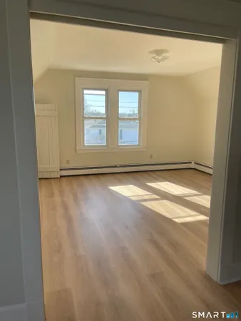 a view of an empty room with wooden floor and a window