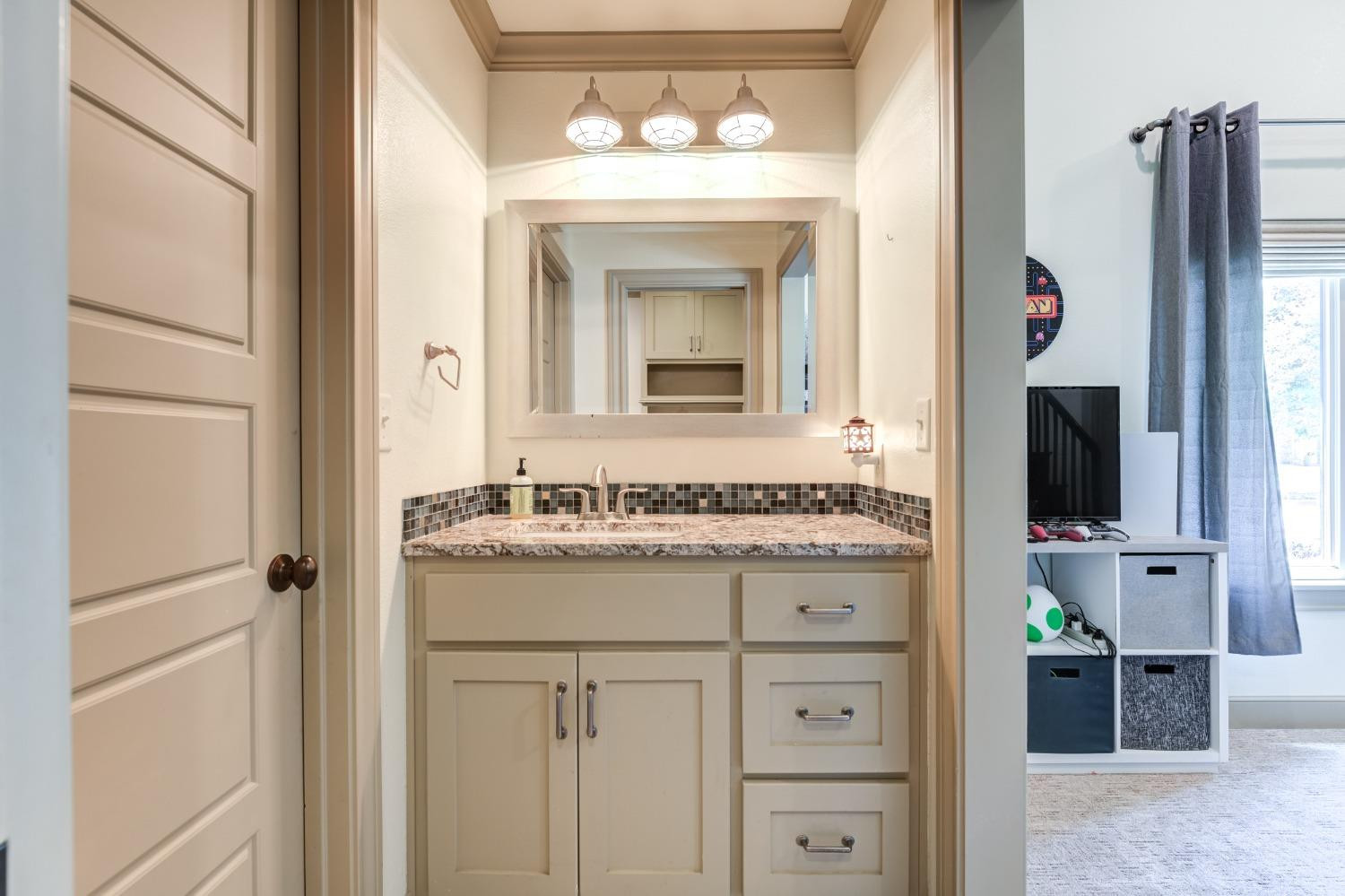 4808 115th Street Lubbock, TX 79424 - Photo 24 of 50 a bathroom with a granite countertop sink a mirror and a shower