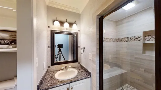 a bathroom with a granite countertop sink a mirror and shower