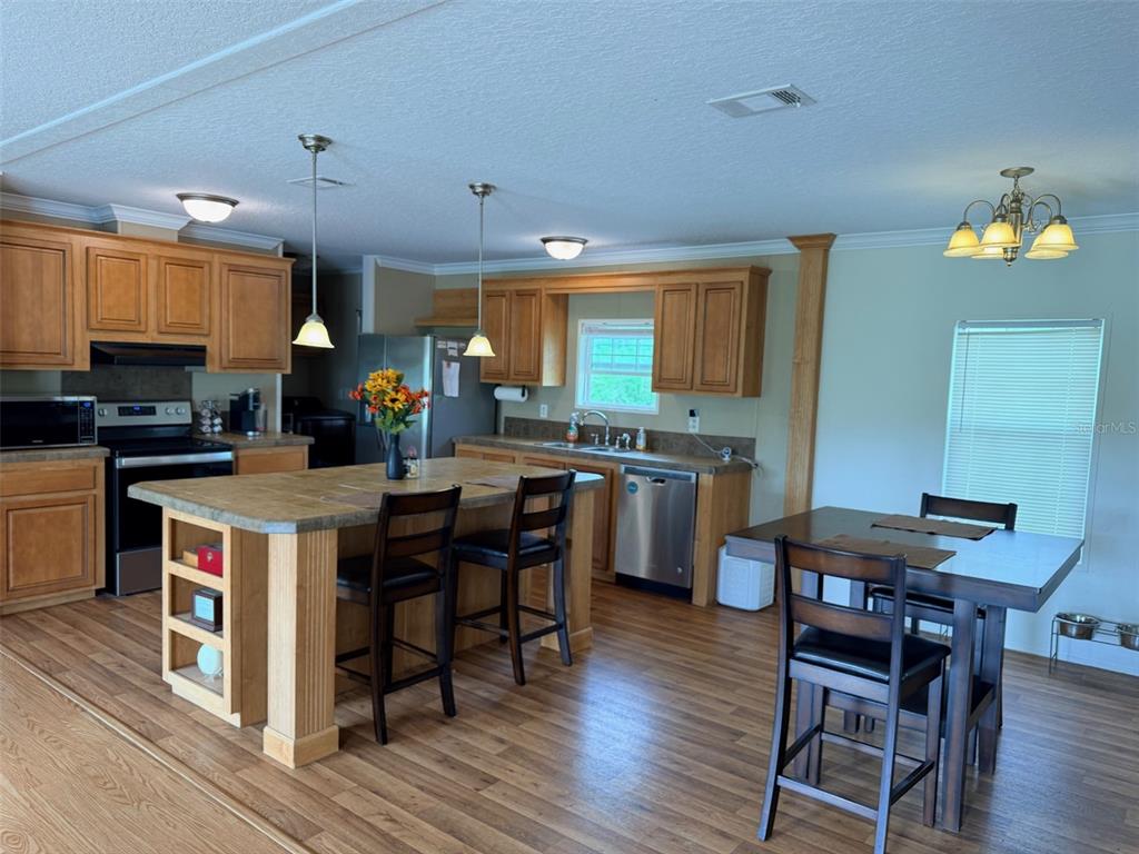 10730 198th Terrace O'Brien, FL 32071 - Photo 3 of 29 a kitchen with a table chairs a sink dishwasher stove and cabinets with wooden floor