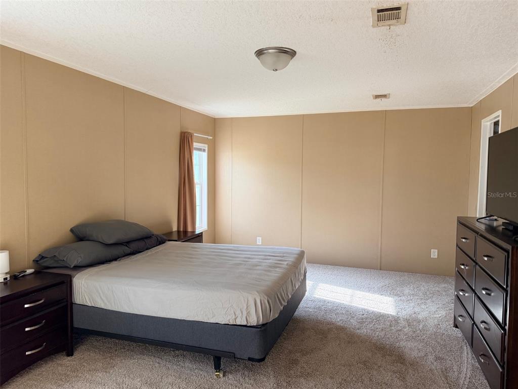 10730 198th Terrace O'Brien, FL 32071 - Photo 5 of 29 a bedroom with a bed and a flat tv screen on dresser