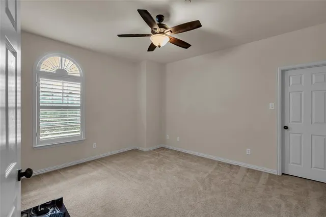 an empty room with windows and ceiling fan