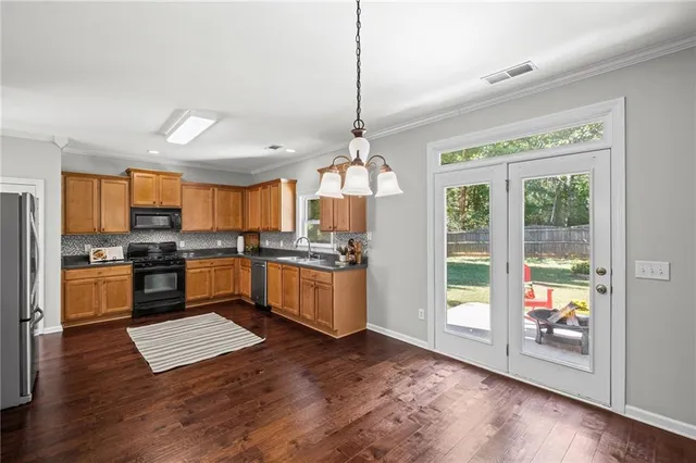 a view of an empty room with chandelier fan and wooden floor