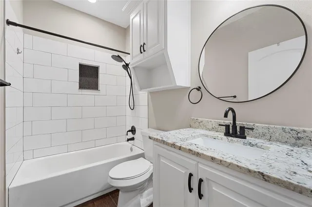a bathroom with a granite countertop sink a toilet and bathtub