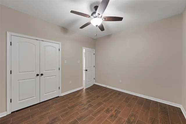 an empty room with wooden floor ceiling fan and windows