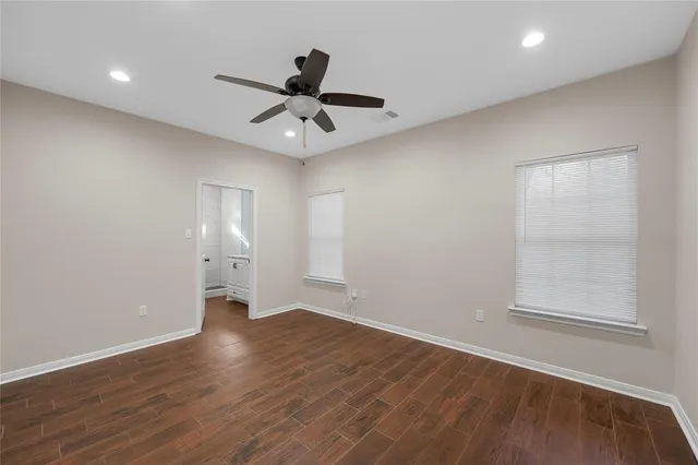 a view of an empty room with a window and wooden floor