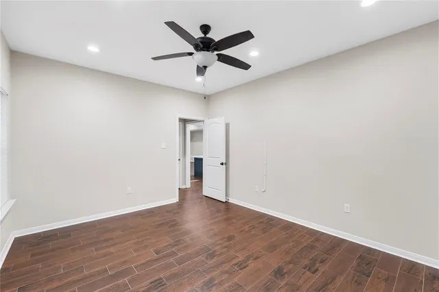 an empty room with wooden floor and ceiling fan