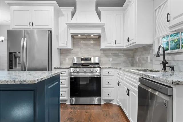 a kitchen with stainless steel appliances granite countertop a stove a sink and a refrigerator