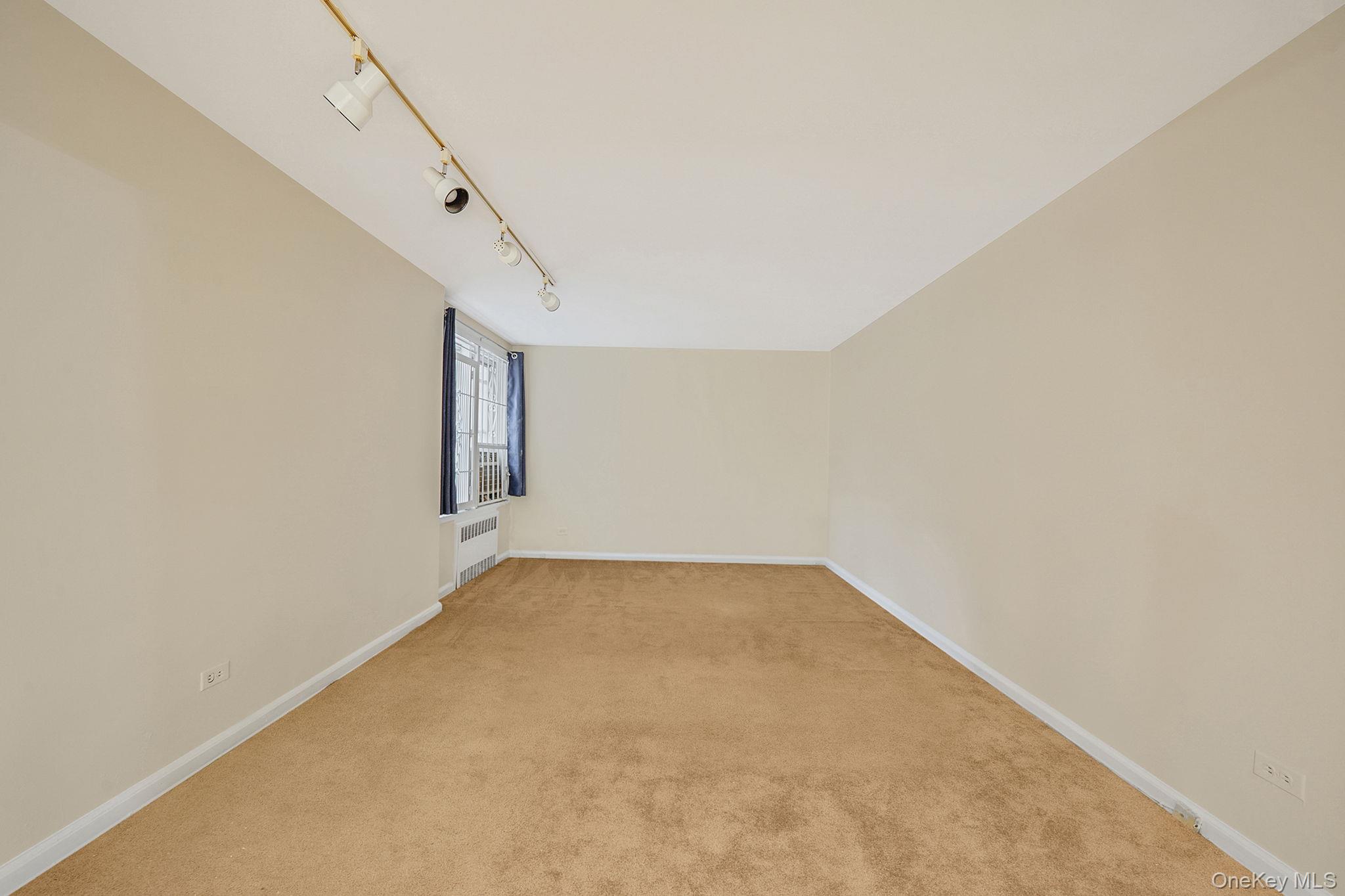 35-40 75th Street, Unit 1B Queens, NY 11372 - Photo 10 of 19 Additional living space with carpet and radiator heating unit