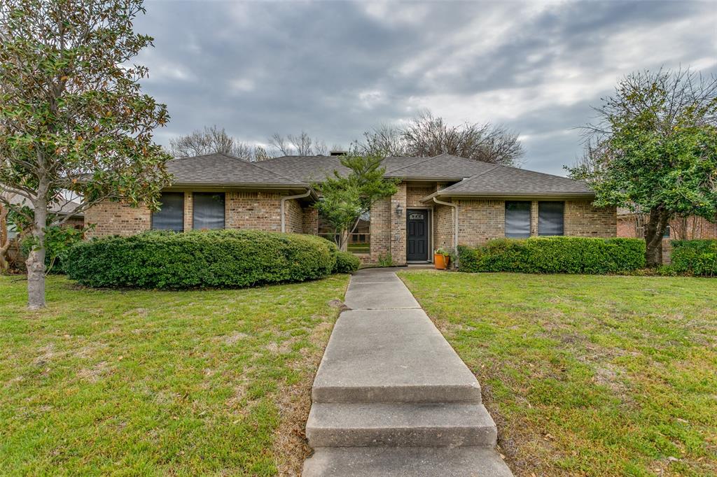 View of front of house featuring brick siding, roof with shingles, and a front lawn