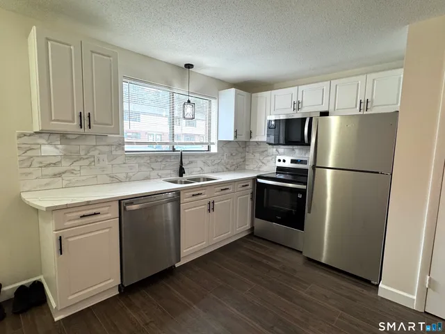 a kitchen with a refrigerator a sink dishwasher a stove and white cabinets with wooden floor