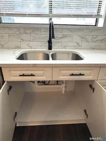 a kitchen with stainless steel appliances a sink dishwasher a refrigerator a stove top oven a counter space and cabinets