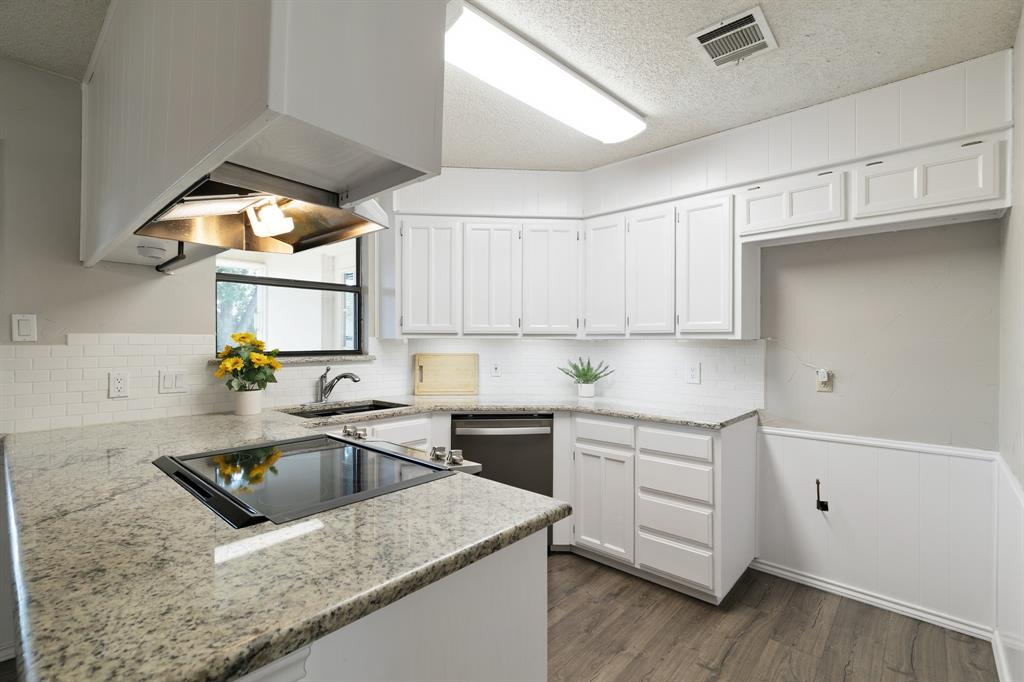 6612 Patsy Lane Watauga, TX 76148 - Photo 11 of 32 Kitchen featuring white cabinetry, granite-finish countertops, subway tile backsplash, stainless steel sink, and wood-finish flooring