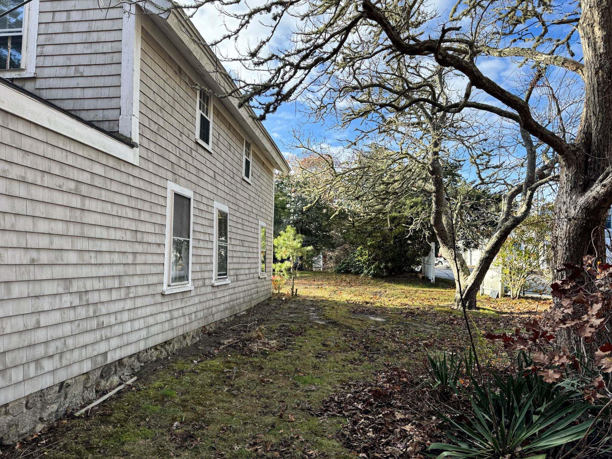 30 Pond Street Osterville, MA 02655 - Photo 9 of 26 a backyard of a house with large trees and wooden fence