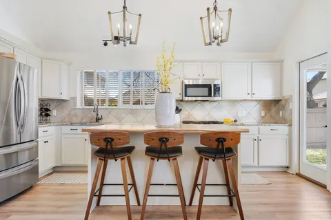 a kitchen with stainless steel appliances granite countertop a sink a stove a refrigerator and cabinets