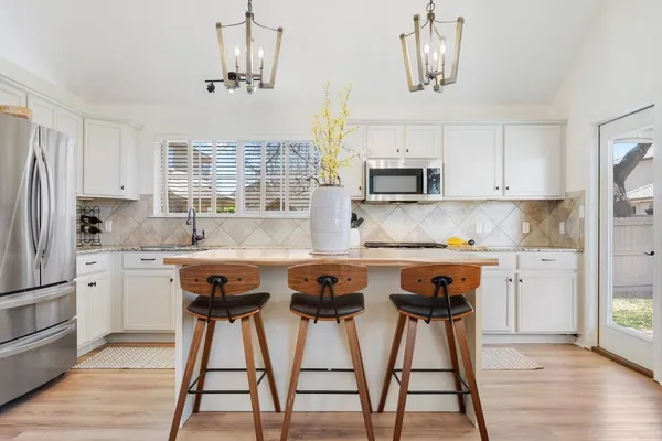 a kitchen with stainless steel appliances granite countertop a sink a stove a refrigerator and cabinets