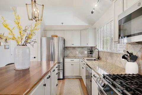 a kitchen with stainless steel appliances granite countertop a sink stove and refrigerator