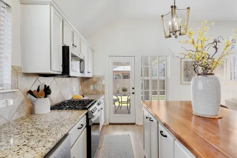 a kitchen with stainless steel appliances granite countertop a sink a stove top oven a counter space and cabinets