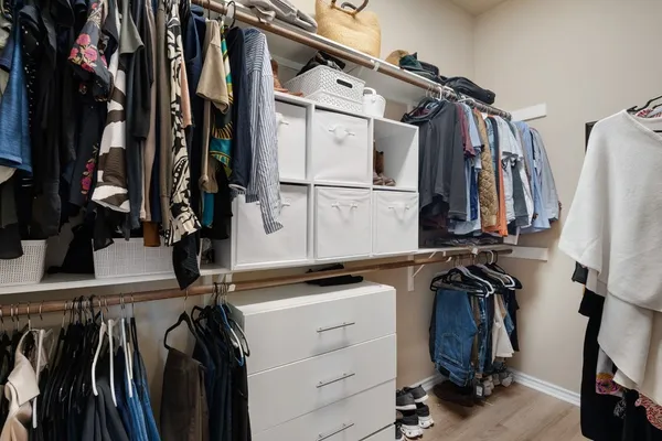 a view of walk in closet with clothes and shoes