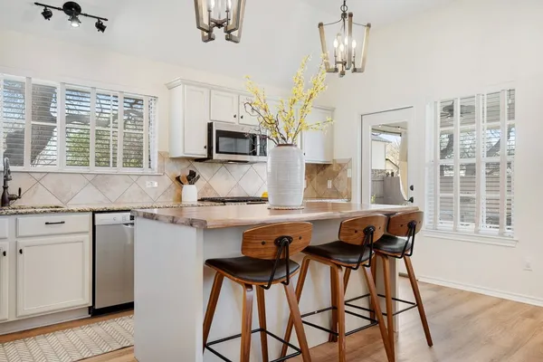 a kitchen with stainless steel appliances granite countertop a stove a sink dishwasher a dining table and chairs with wooden floor