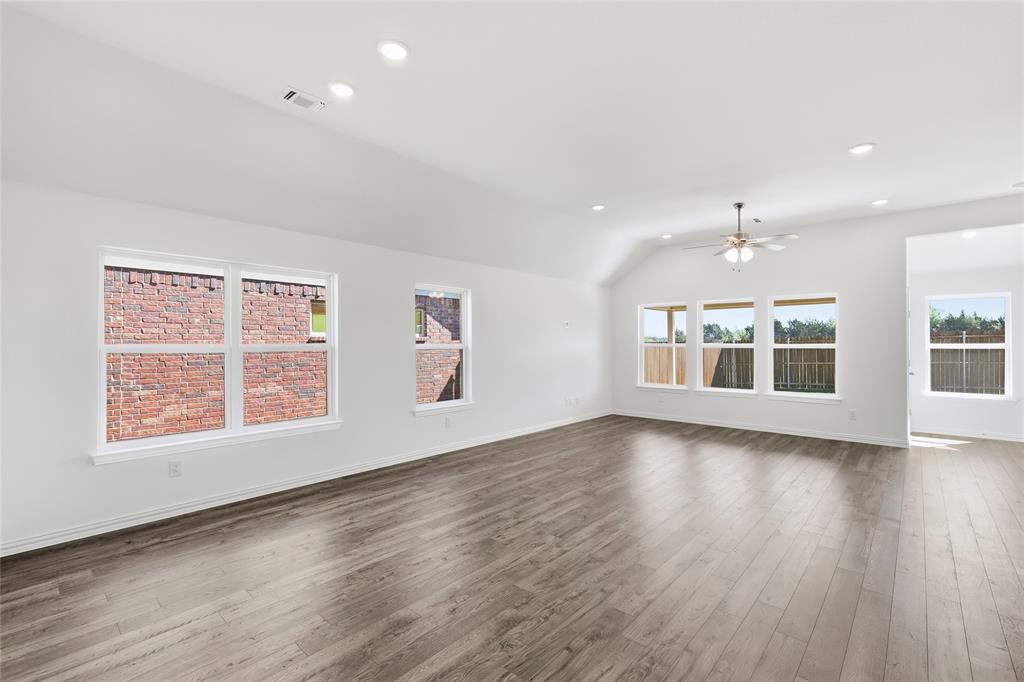 2529 Rivers W Road Anna, TX 75409 - Photo 18 of 40 Open-concept living area featuring wood-finish flooring, white walls, and a vaulted ceiling