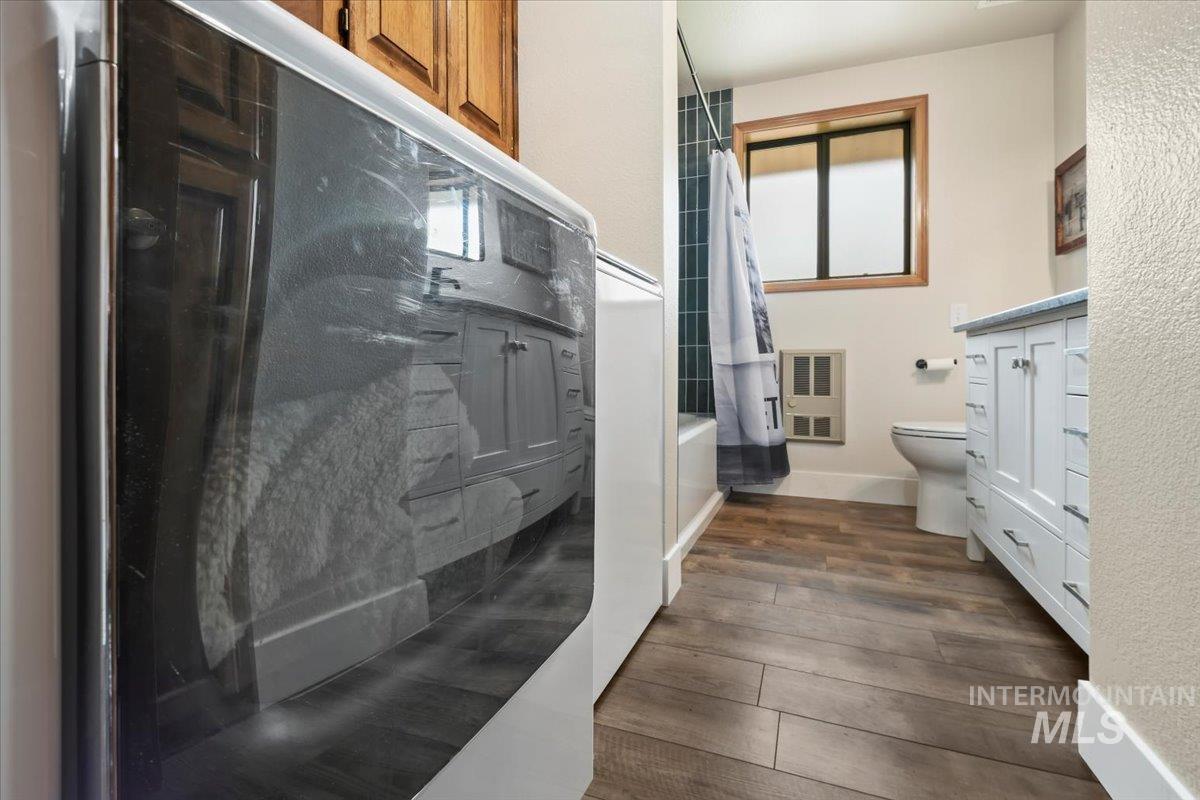 76 West Castle Creek Road Garden Valley, ID 83622 - Photo 16 of 46 Bathroom with wood finished floors, heating unit, shower / bathtub combination with curtain, and vanity