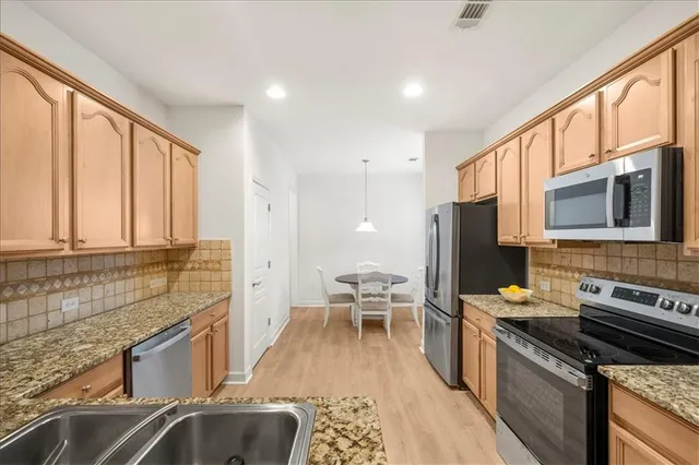 a kitchen with stainless steel appliances granite countertop a stove a sink and a microwave