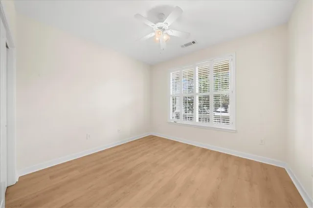 an empty room with a window and a ceiling fan