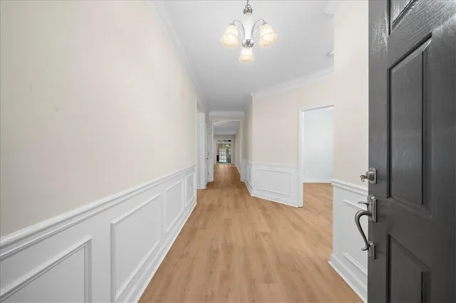 a view of a hallway with wooden floor and chandelier