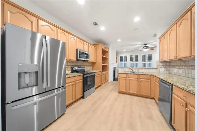 a kitchen with stainless steel appliances granite countertop a refrigerator stove top oven and sink