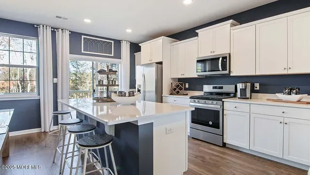 a open kitchen with stainless steel appliances granite countertop a stove a sink dishwasher a microwave oven and a refrigerator with wooden floor
