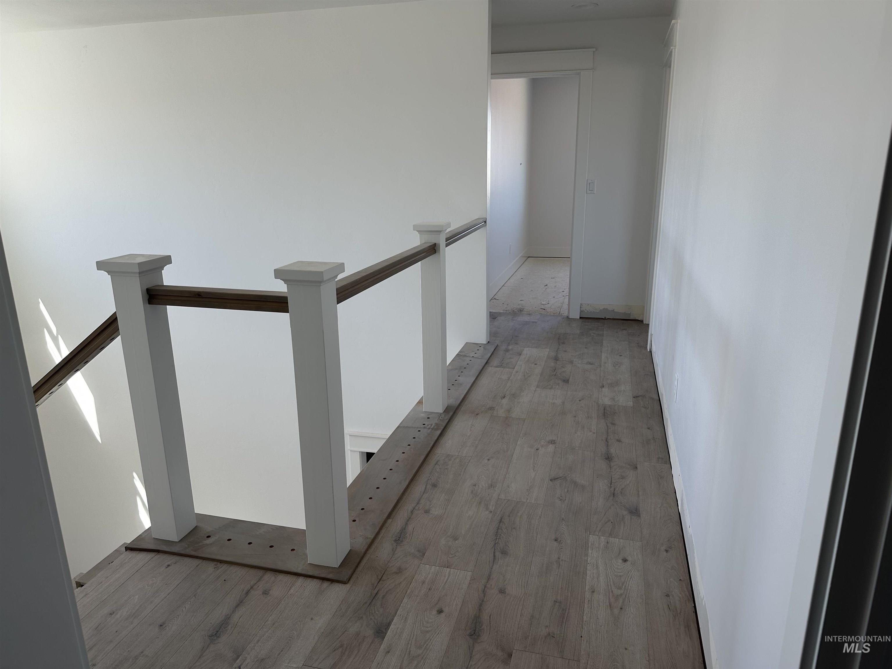 3035 Lake View Twin Falls, ID 83301 - Photo 8 of 18 Upper-level hallway featuring wood-finish flooring, a white painted railing with a contrasting wood-tone handrail, and white walls