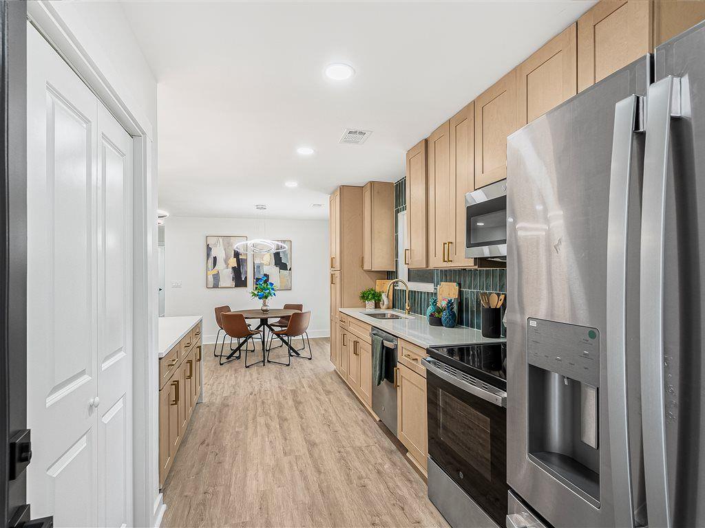 531 Carlton Road Palmetto, GA 30268 - Photo 14 of 38 a kitchen with stainless steel appliances a refrigerator a stove a sink dishwasher and white cabinets with wooden floor