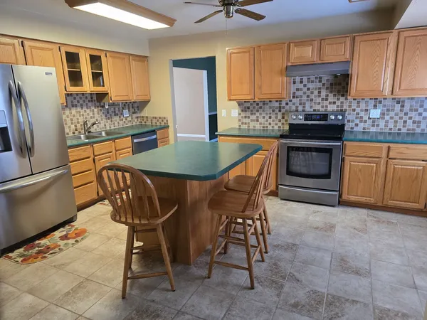 a kitchen with stainless steel appliances granite countertop a sink a stove a microwave a counter top space and cabinets