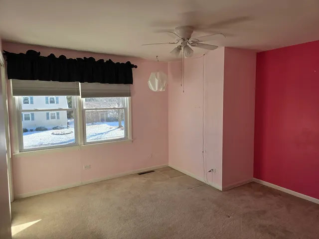 an empty room with a ceiling fan and a window
