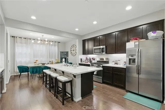 a kitchen with stainless steel appliances granite countertop a stove refrigerator sink dining table and chairs