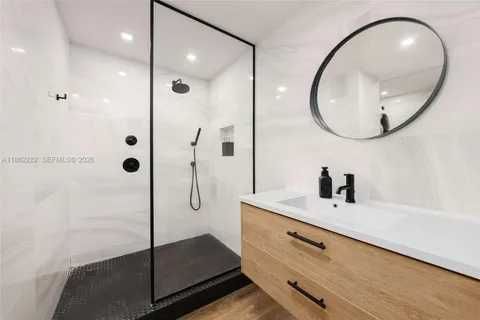 a bathroom with a sink a mirror a vanity and shower