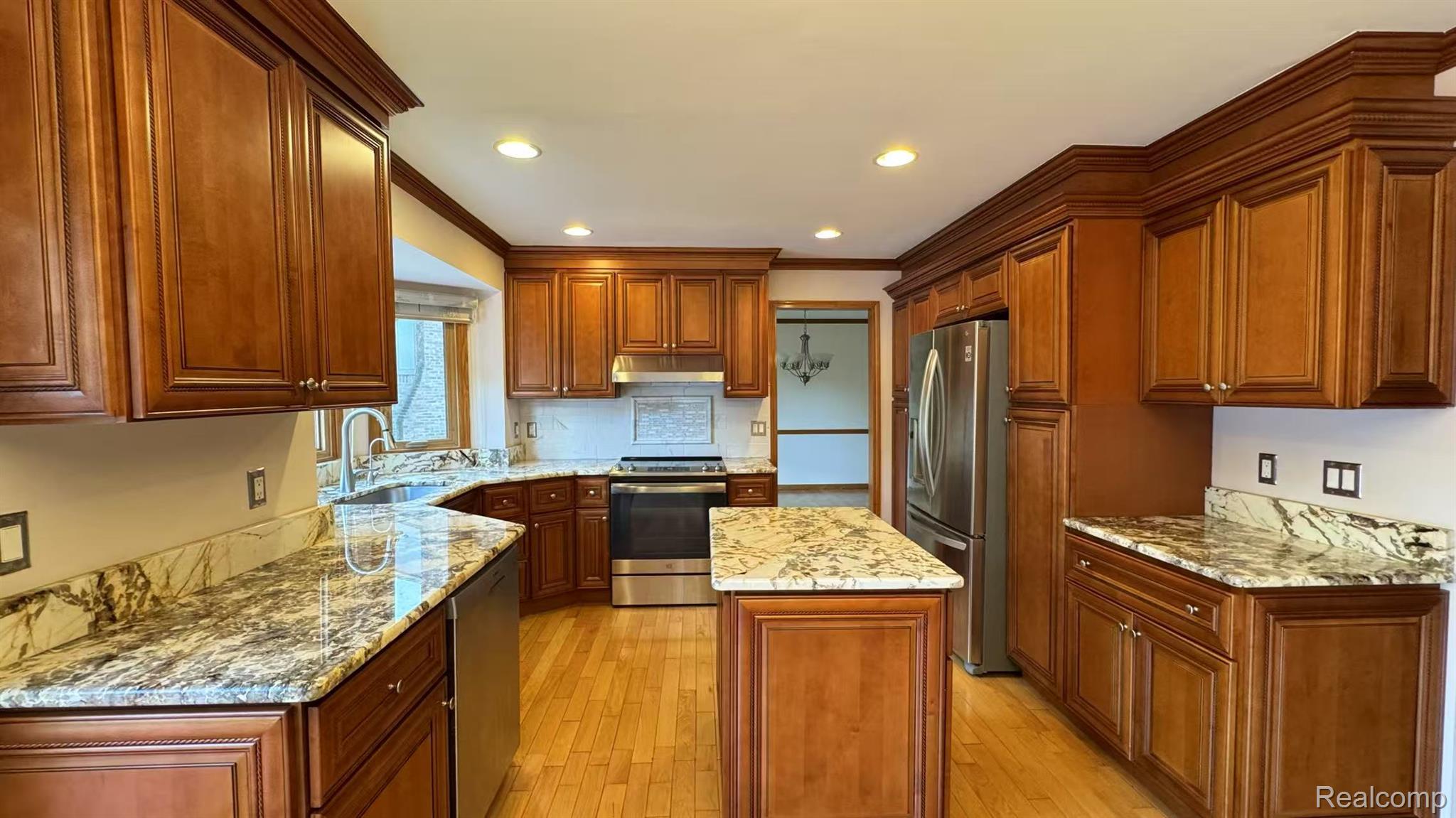 3440 Salem Drive Rochester, MI 48306 - Photo 12 of 33 Kitchen featuring wood-finish cabinetry, light-toned countertops, a central island, stainless steel appliances, and wood-finish flooring