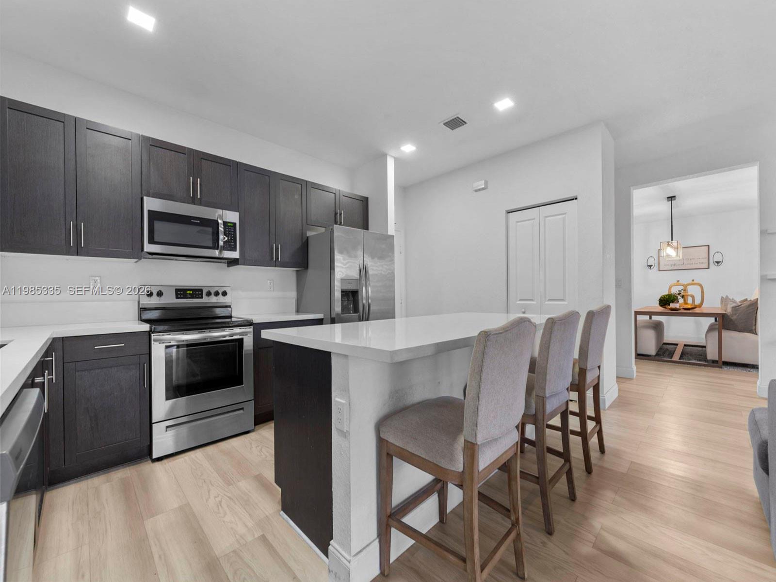 13391 Southwest 285th Street Homestead, FL 33033 - Photo 18 of 37 a kitchen with granite countertop a stove top oven a sink dishwasher a dining table and chairs with wooden floor
