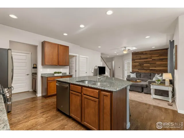 a kitchen with stainless steel appliances granite countertop a stove top oven a sink dishwasher and a refrigerator with wooden floor