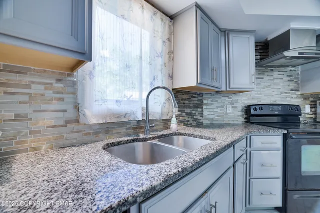 a kitchen with granite countertop a sink a stove and cabinets