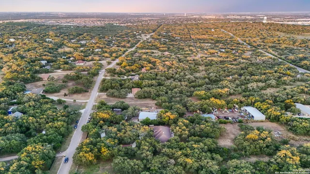 an aerial view of a house and a yard and trees all around