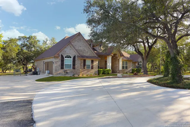 a front view of a house with garden and trees