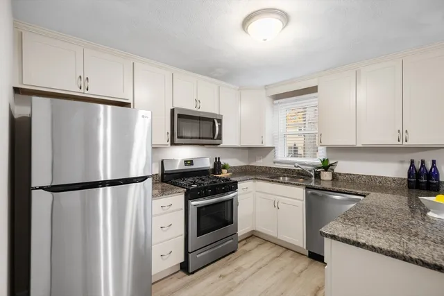 a kitchen with granite countertop a refrigerator stove and sink